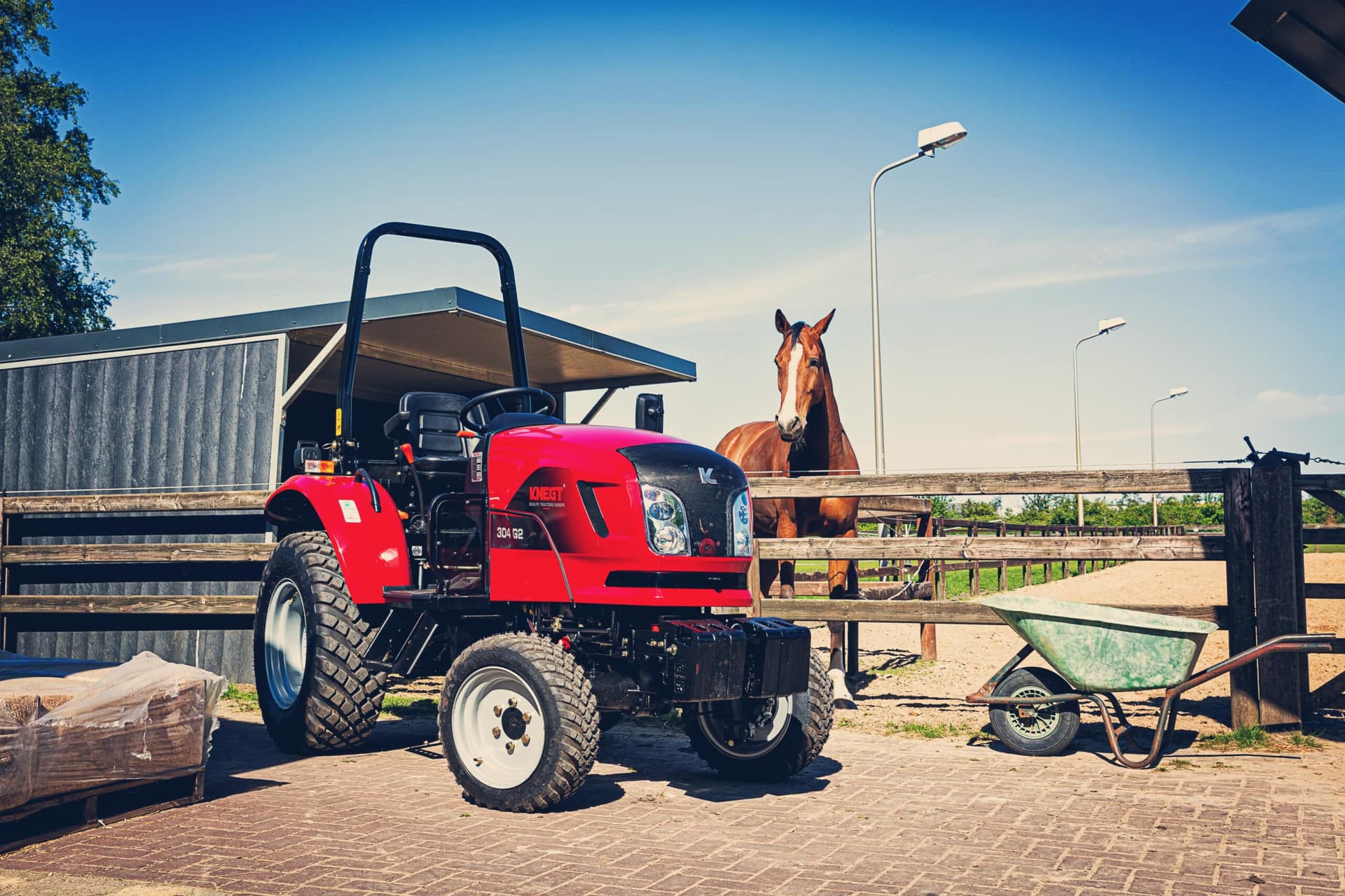 Tractor diésel junto a una cuadra con un caballo