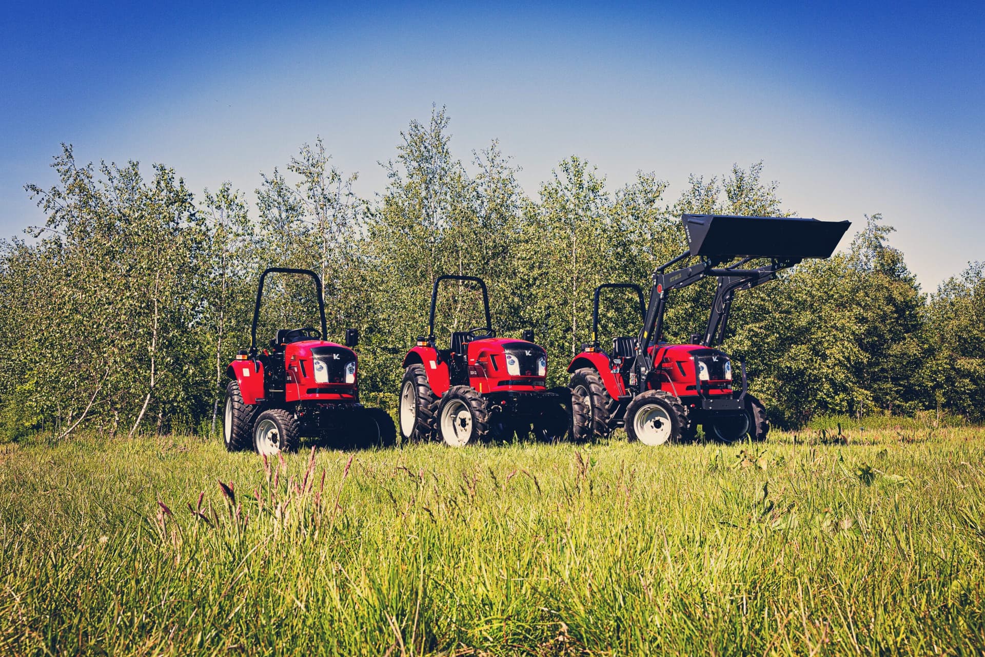 Tres tractores diésel rojos en un prado