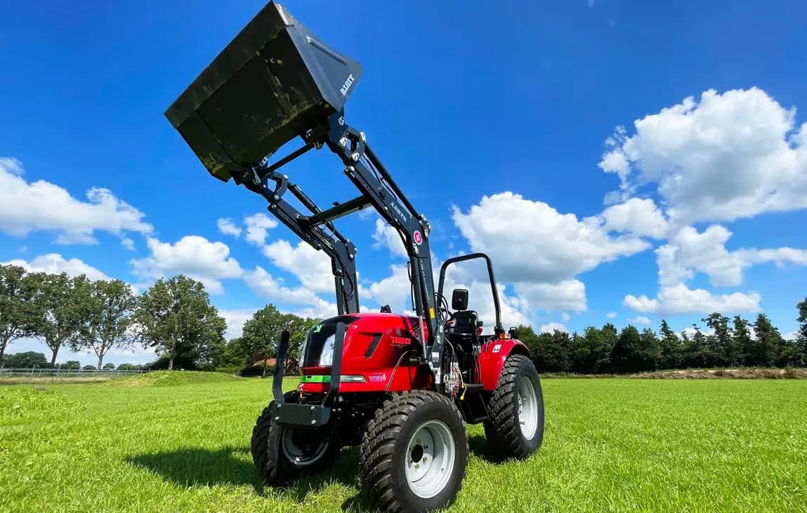 Tractor eléctrico con cargador frontal sobre la hierba