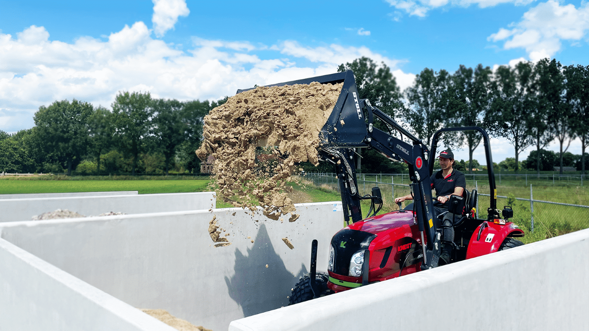 Traktor mit Frontlader, der Sand ablädt